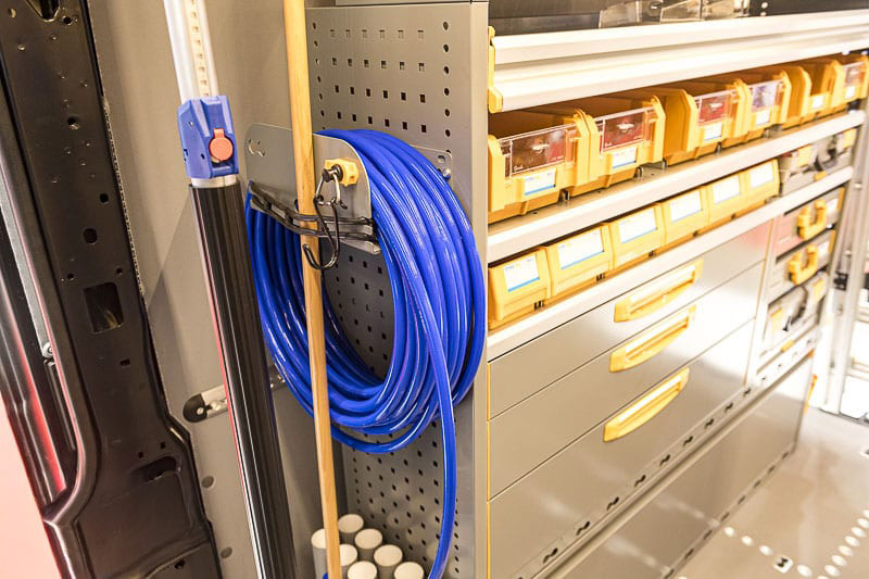 Les grilles latérales des meubles sont perforées et peuvent recevoir de nombreux accessoires, ici un porte tuyau / porte outils.